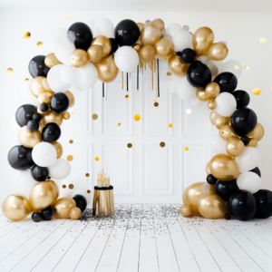 high quality studio photography backdrop with a gold, white, and black balloon arch. There is confetti on the floor. The background is a white wall. It is bright and airy. Shot with AF-S DX VR Zoom-Nikkor ED 55-200mm F4-5.6G lens --ar 1:1 --v 5.2